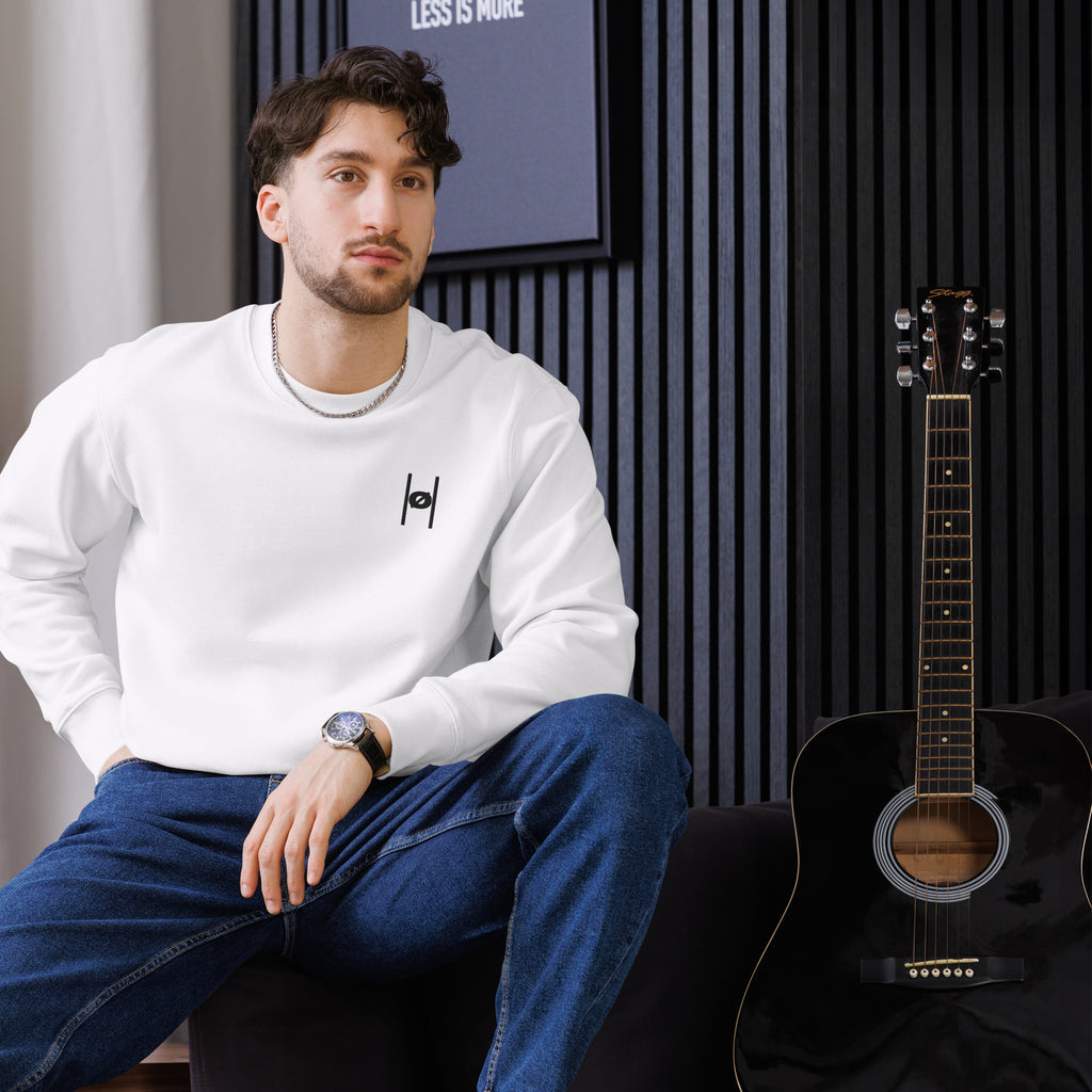 Man sitting next to a guitar in a room with a striped wall.